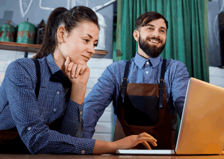 2 people in a cafe on a laptop