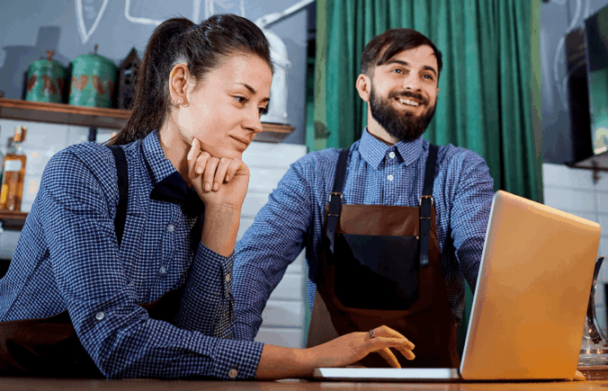 2 people in a cafe on a laptop
