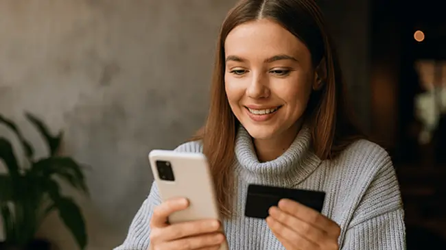 Person smiling looking at phone and credit card