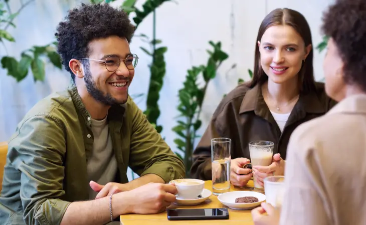 Person smiling at a table in a cafe